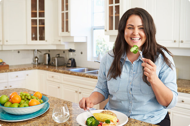 Woman Eating Healthy Meal In Kitchen